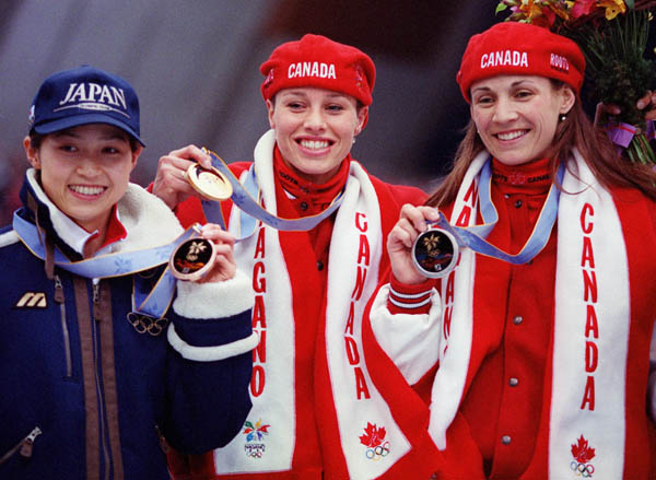 Canada's Catriona Le May Doan (center) and Susan Auch (right) hold up the gold and silver medals they won in the women's long track speed skating event at the 1998 Nagano Winter Olympics. (CP PHOTO/COA)