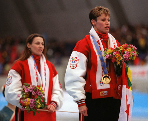 Canada's Susan Auch (L) and Catriona Le May Doan stand on the winners block after receiving the gold and silver medals for the long track speed skating event at the 1998 Nagano Winter Olympics. (CP PHOTO/COA)
