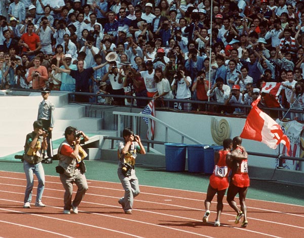 Canada's Ben Johnson waves the Canadian flag in front of photograpers after winning the 100m event at the 1988 Olympic games in Seoul. (CP PHOTO/ COA/ Cromby McNeil)