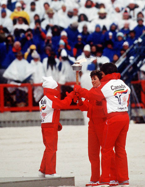 Canada's Robyn Perry (left) receives the olympic toarch from Cathy Preistner (centre) and Ken Read during the opening ceremonies of the 1988 Winter Olympics in Calgary. (CP PHOTO/COA/ T. O'lett)
