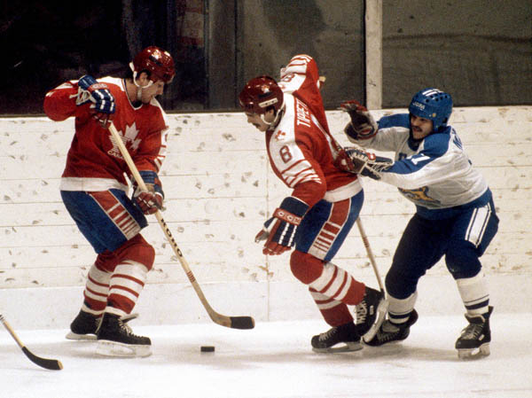 Canada's Dave Tippett (centre) takes a check during hockey action against Finland at the 1984 Winter Olympics in Sarajevo. (CP PHOTO/ COA/J. Merrithew)