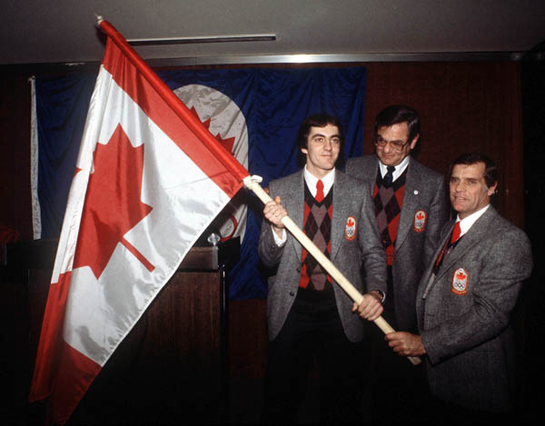 COA officials present Canada's speedskater Gaetan Boucher (left) with the Canadian flag at the 1984 winter Olympics in Sarajevo. (CP Photo/ COA/ O. Bierwagon)