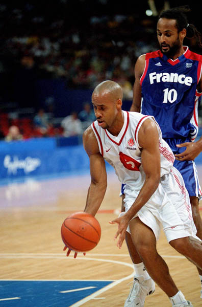 Canada's Greg Francis (front) gets a grip on the ball during basketball action at the 2000 Sydney Olympic Games. (CP Photo/ COA)