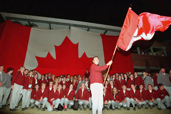 Canada's flag bearer Caroline Brunet waves the Maple Leaf as Olympic Team members watch at the 2000 Sydney Olympic Games. (CP Photo/ COA)