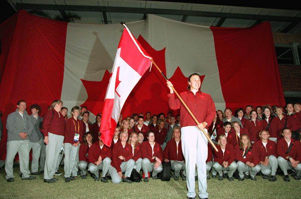 Canada's flag bearer Caroline Brunet waves the Maple Leaf as Olympic Team members watch at the 2000 Sydney Olympic Games. (CP Photo/ COA)