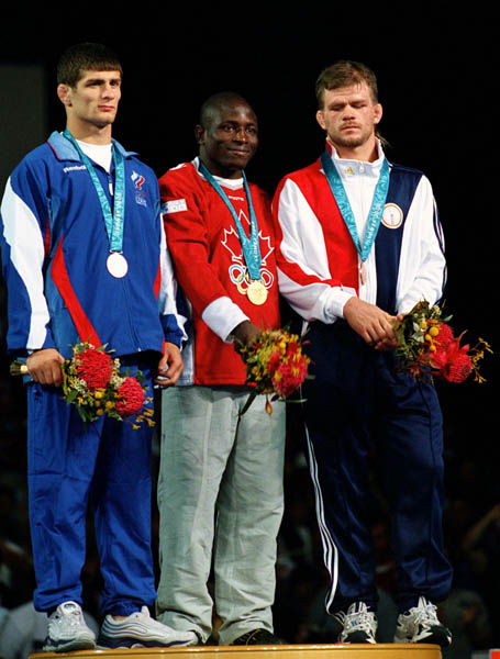 Canada's Daniel Igali (centre) celebrates his gold medal win in the wrestling event at the 2000 Sydney Olympic Games. (CP PHOTO/ COA)