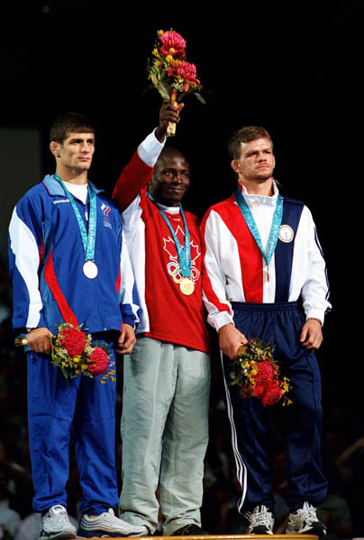 Canada's Daniel Igali (centre) celebrates his gold medal win in the wrestling event at the 2000 Sydney Olympic Games. (CP PHOTO/ COA)