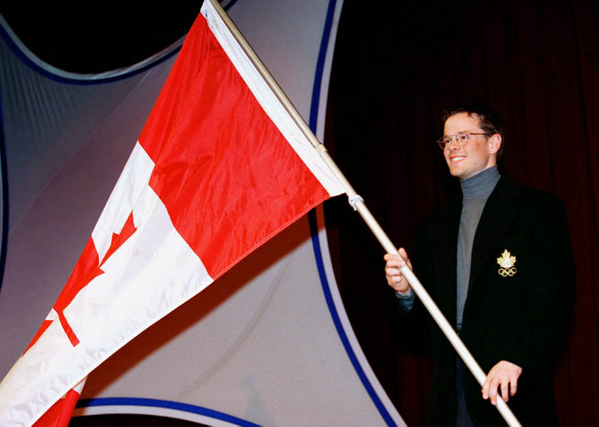 Canada's Jean-Luc Brassard holds the Canadian flag during his nomination as the flag bearer at the 1998 Nagano Winter Olympics. (CP PHOTO/COA/F. Scott Grant)