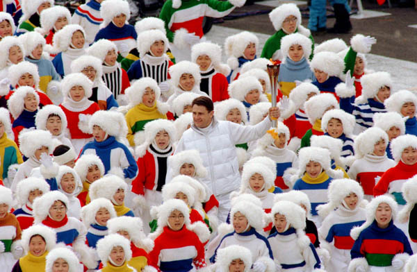 Participants escort a torch bearer (centre) during the opening ceremony of the 1998 winter Olympic Games in Nagano. (CP Photo/ COA/F. Scott Grant)