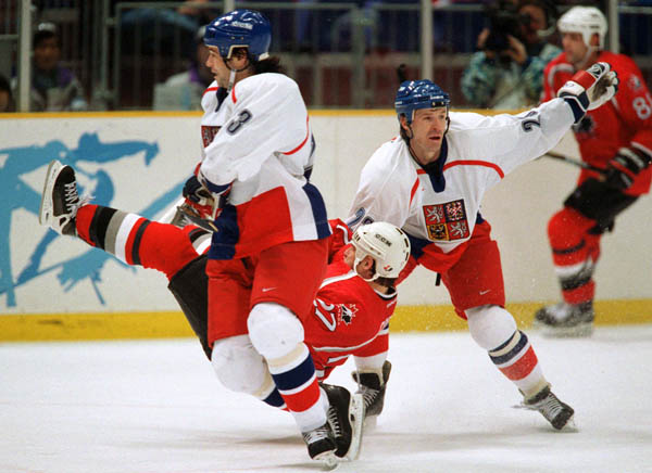 Canada's Shayne Corson (centre) is upended during  hockey action at the 1998 Winter Olympics in Nagano. (CP Photo/COA/ F. Scott Grant )