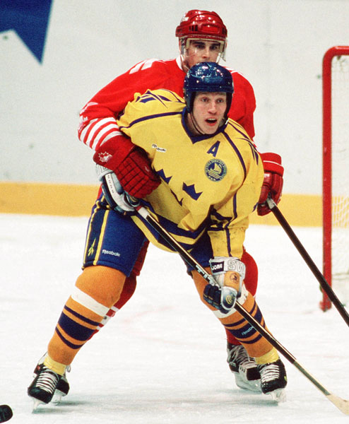 Canada's Ken Lovsin (red) competes in hockey action against Sweden at the 1994 Winter Olympics in Lillehammer. (CP Photo/COA/Claus Andersen)