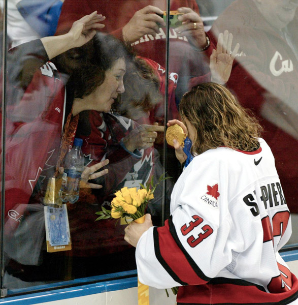 La gardienne de but de l'quipe fminine canadienne de hockey Kim St-Pierre de Chateauguay, Qubec, montre sa mdaille d'or aux parents et aux amis,  travers la vitre, aprs que l'quipe canadienne ait remport l'or sur celle des tats-Unis avec un score