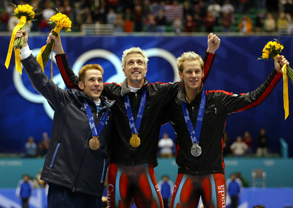Canadian Short Track gold medallist Marc Gagnon (C) and Canadian silver medallist Jonathan Guilmette (R) along with USA bronze medallist Rusty Smith (L) wave to the crowd after the Men's 5000 metre Relay Saturday Feb. 23, 2002 at the 2002 Winter Olympic G