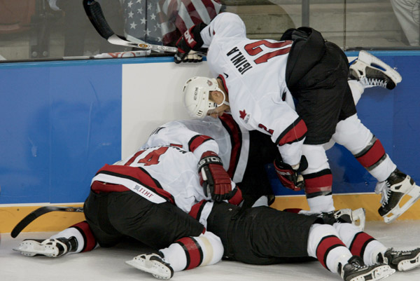 Players including Jarome Iginal (12) and Theoren Fleury (14) mob Joe Sakic (bottom) after he scored Canada's fifth goal in a 5 - 2 gold medal game victory over the U.S.l at the Winter Olympics in Salt Lake City, Utah, Sun., Feb. 24, 2002 . (CP PHOTO/COA/M
