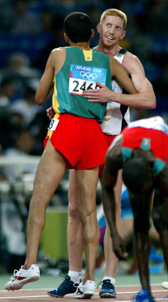 Canada's Kevin Sullivan (right) of Brantford, Ont. hugs Hicham El Guerrouj of Morocco after Sullivan failed to qualify in the men's 1500 metres in track and field action at the Athens Olympics, Sunday, August 22, 2004.(CP PHOTO/COC-Mike Ridewood)