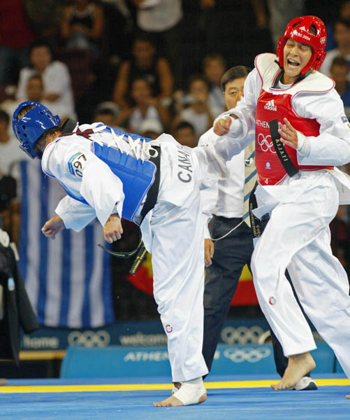 Canada's Dominique Bosshart (blue) of Winnipeg competes with Daniela Castrignano of Italy in the women's plus 67kg taekwondo at the Athens Olympics on Sunday Aug. 29, 2004. Bosshart lost 7-5 to Myriam Baverel, France, in first round, then was eliminated when she was beaten 7-3 by Castrignano in a second-chance repechage. (CP PHOTO/COC-Mike Ridewood)
