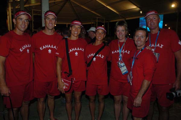 Canada's 2004 beach volleyball team during the Canadian flag raising ceremony at the Olympic Games in Athens.  From left to right: Mark Heese, John Child, Guylaine Dumont, Annie Martin, Caroline Sharp (executive director, Volleyball Canada), Vincent Larive (coach) and John May (team leader). (CP PHOTO 2004/Andre Forget/COC)