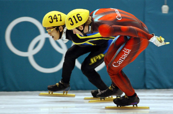 Canadian Short Track speed skaters Jonathan Guilmette races against a Japanese skater at the 2002 Olympic Winter Games in Salt Lake City.  (CP Photo/COA/Andre Forget).