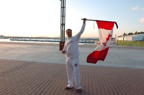 Canada's Oskar Johansson of Oakville, Ontario, waves the Canadian flag.  Johansson and his partner John Curtis finished 15th in the tornado sailing event at the 2004 Summer Olympic Games in Athens. (CP PHOTO 2004/Andre Forget/COC)
