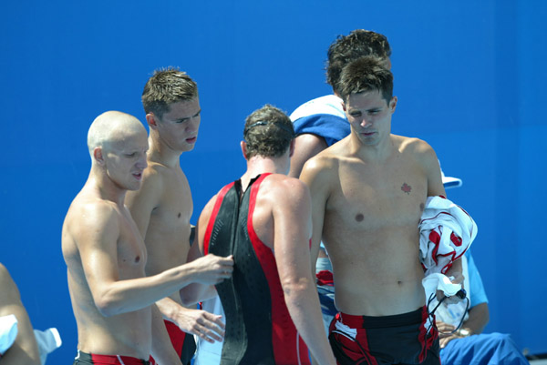 Canada's Brian Johns of Richmond, BC, unzips Rick Say of Victoria while Andrew Hurd of Toronto, and Mark Johnston of St. Catharines, Ontario, (left to right) watch. Canadas mens 4X200m freestyle relay team finished third overall in their heat at the 2004 Summer Olympic Games in Athens, Greece, Tuesday Aug 17, 2004 and advanced to the final where they finished fifth. (CP PHOTO)2004(COC-Mike Ridewood)