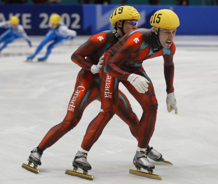 Canadian short track speed skater Mathieu Turcotte (319) pushes off teammate Marc Gagnon (315) during the Relay 5,000 metre heat in Salt Lake City at the 2002 Olympic Winter Games. (CP Photo/COA/Andre Forget).