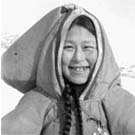 Photograph of a young Inuit woman standing in a snowy landscape, unknown location, Nunavut, no date